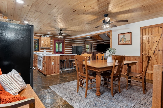 dining space with ceiling fan, wooden ceiling, and wood walls