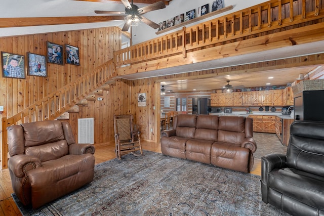 living room with a towering ceiling, hardwood / wood-style flooring, wood walls, and beamed ceiling