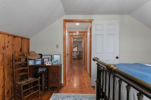 bedroom with hardwood / wood-style floors, a textured ceiling, and vaulted ceiling