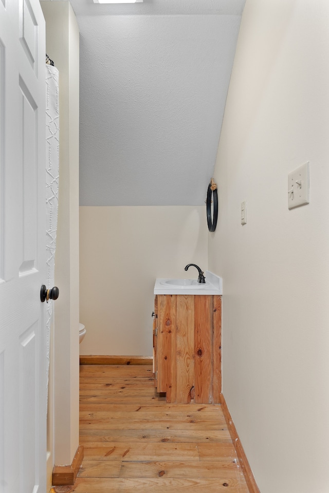 bathroom with vanity, vaulted ceiling, hardwood / wood-style flooring, and toilet