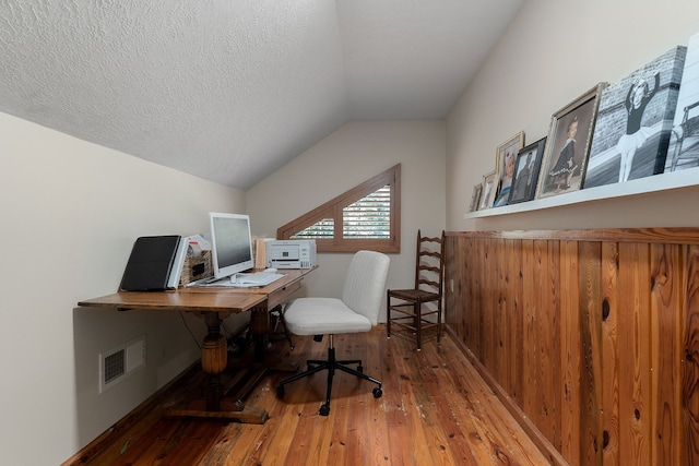 office area featuring a textured ceiling, lofted ceiling, and hardwood / wood-style floors