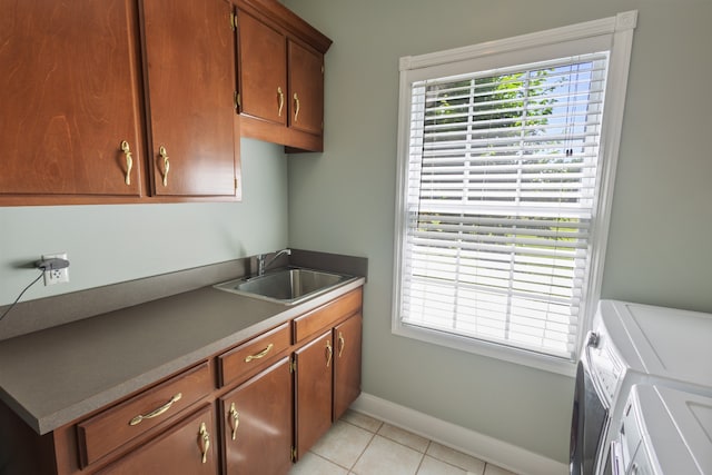 clothes washing area with sink, light tile patterned floors, cabinets, and separate washer and dryer