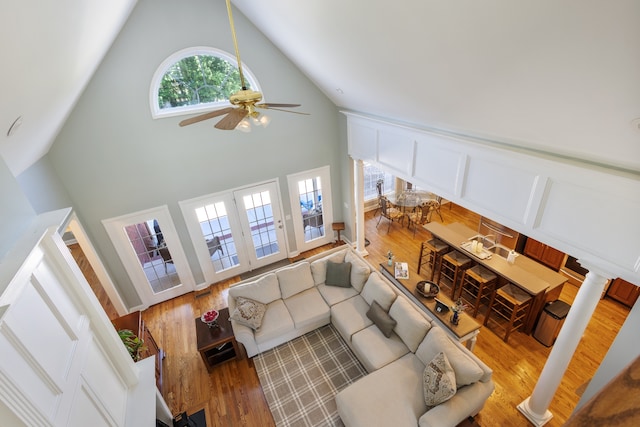 living room featuring hardwood / wood-style flooring, ceiling fan, high vaulted ceiling, and decorative columns