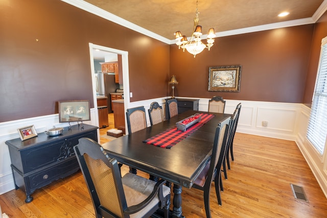 dining space with an inviting chandelier, ornamental molding, and light hardwood / wood-style floors