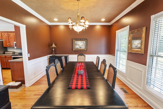 dining area featuring light hardwood / wood-style flooring, a notable chandelier, and crown molding