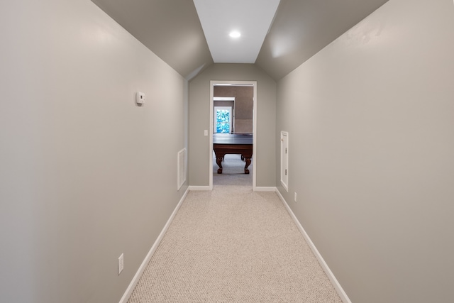 hallway with lofted ceiling and light colored carpet