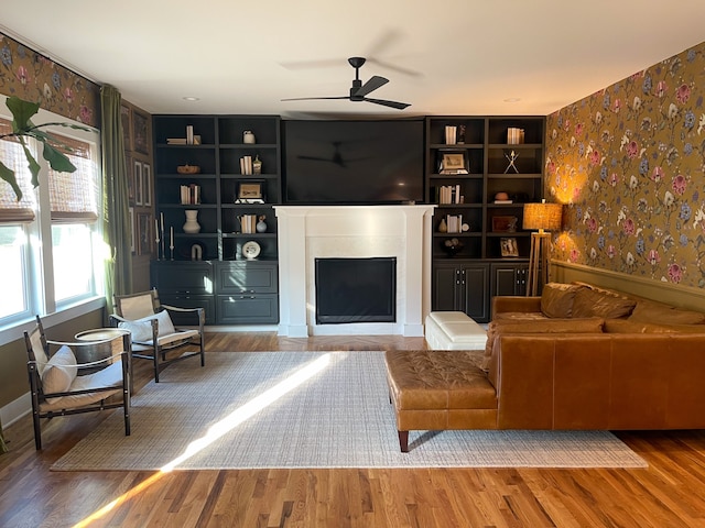 living room featuring ceiling fan, built in shelves, and hardwood / wood-style floors