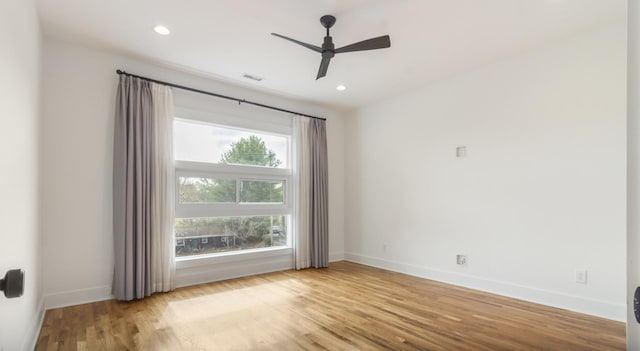 spare room featuring ceiling fan, a wealth of natural light, and light wood-type flooring