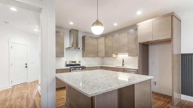 kitchen featuring decorative light fixtures, sink, stainless steel appliances, wall chimney exhaust hood, and light stone counters