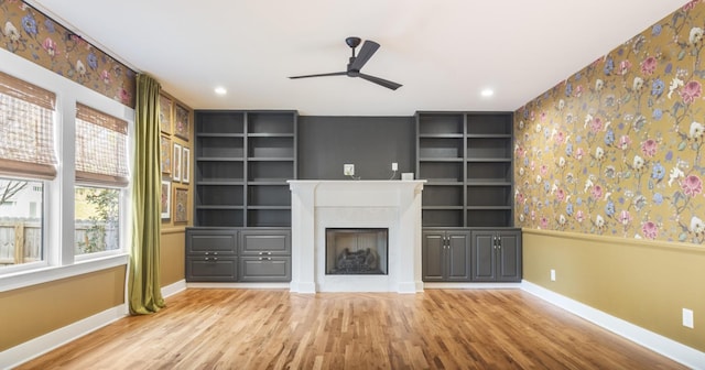 unfurnished living room with ceiling fan, hardwood / wood-style floors, and built in features