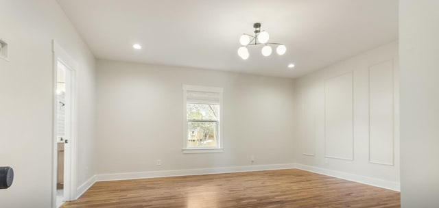 unfurnished room with wood-type flooring and a chandelier