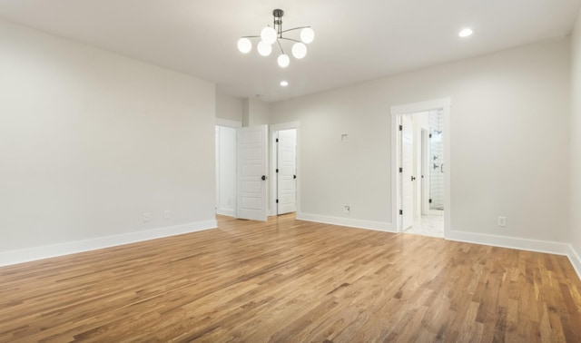 spare room featuring a chandelier and light hardwood / wood-style floors