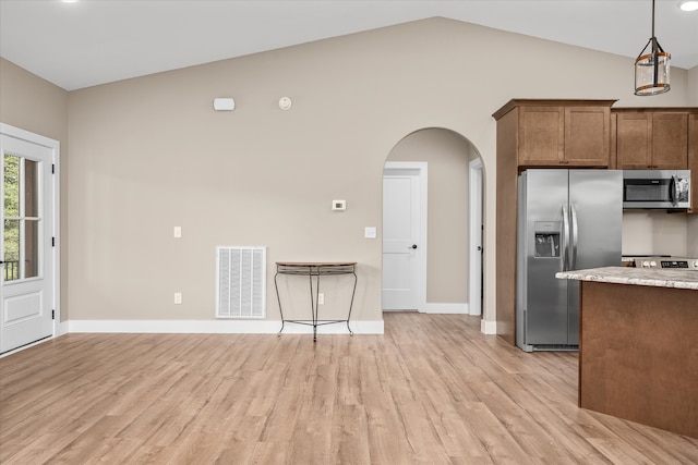 kitchen with light stone countertops, stainless steel appliances, vaulted ceiling, decorative light fixtures, and light hardwood / wood-style flooring