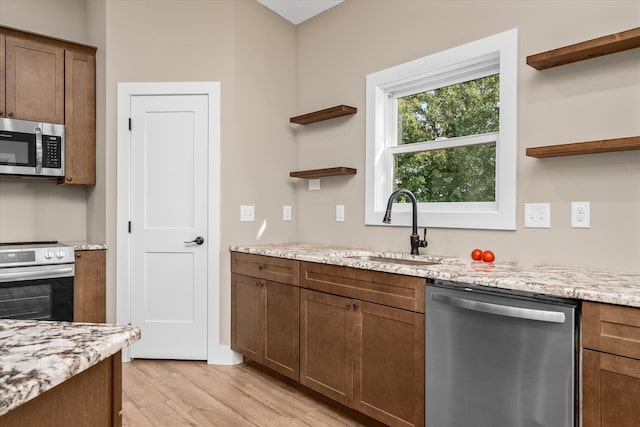 kitchen featuring light hardwood / wood-style floors, stainless steel appliances, sink, and light stone counters