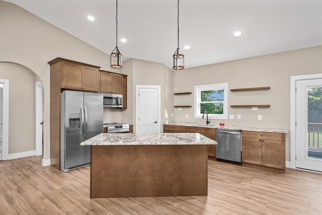 kitchen featuring pendant lighting, vaulted ceiling, stainless steel appliances, and light hardwood / wood-style floors