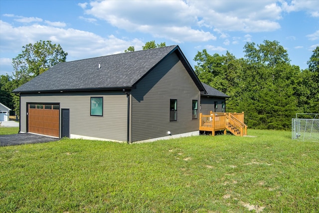 view of side of property featuring a deck, a lawn, and a garage