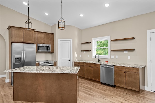 kitchen with sink, vaulted ceiling, pendant lighting, light wood-type flooring, and appliances with stainless steel finishes