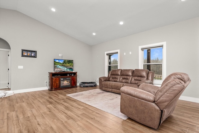 living room with baseboards, high vaulted ceiling, light wood-style flooring, recessed lighting, and arched walkways