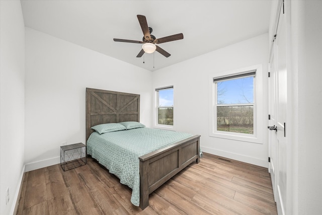 bedroom with light wood-type flooring, baseboards, and a ceiling fan