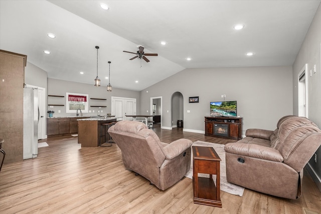 living room with light wood-type flooring, recessed lighting, arched walkways, ceiling fan, and vaulted ceiling