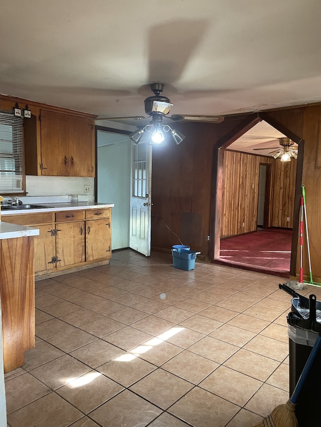 kitchen featuring ceiling fan, wood walls, and light tile patterned floors