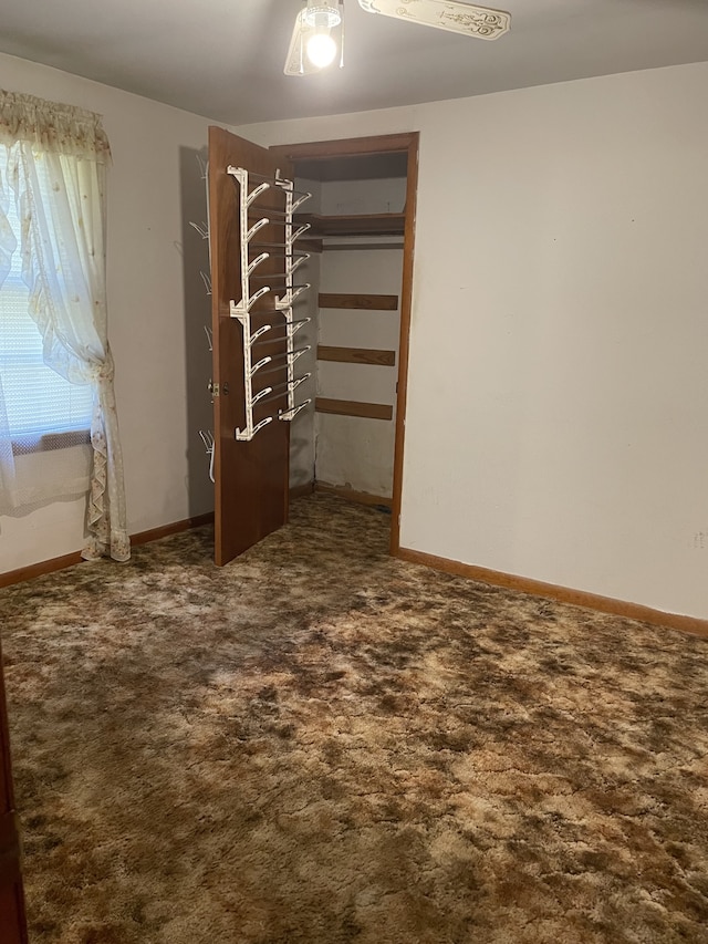 unfurnished bedroom featuring a closet, ceiling fan, and dark colored carpet