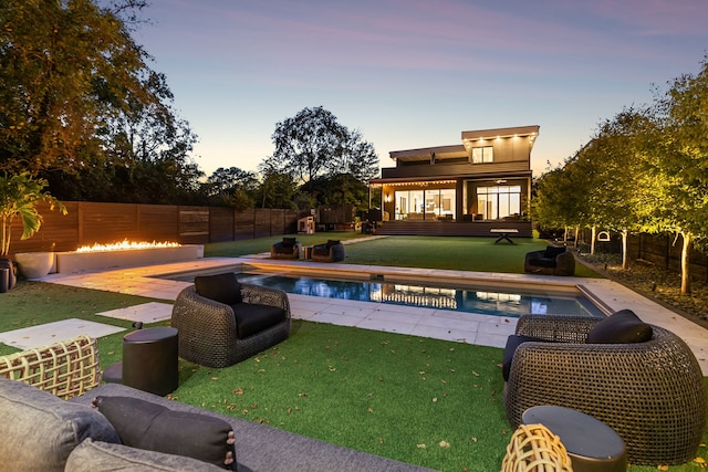 pool at dusk with a patio and a yard