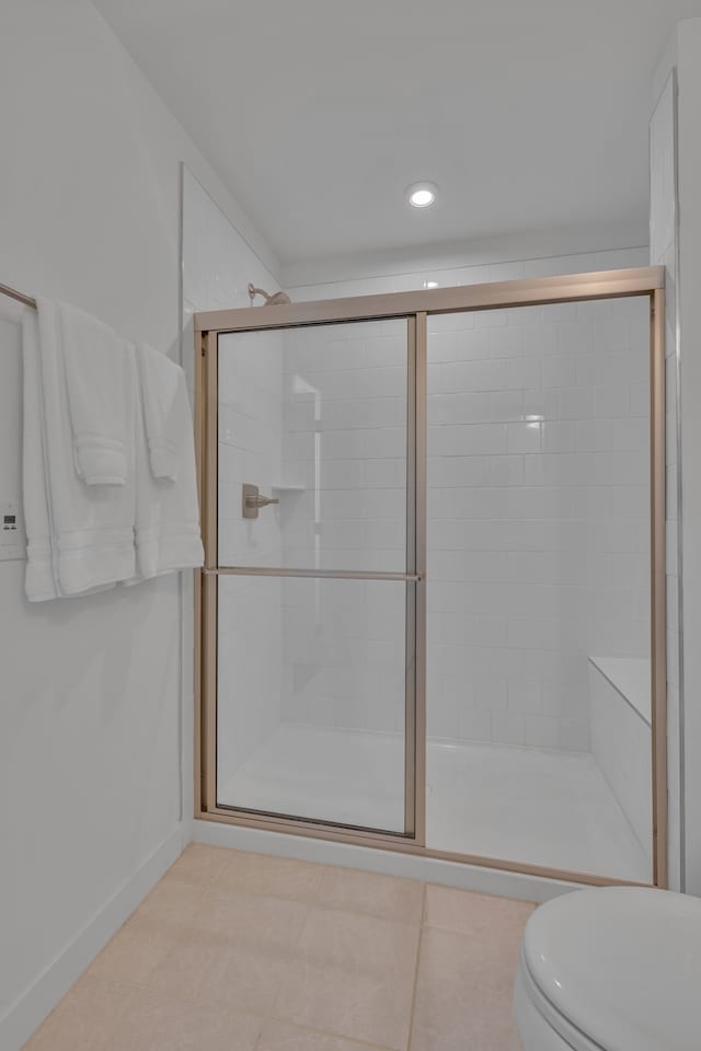 bathroom featuring tile patterned floors, toilet, and a shower with door