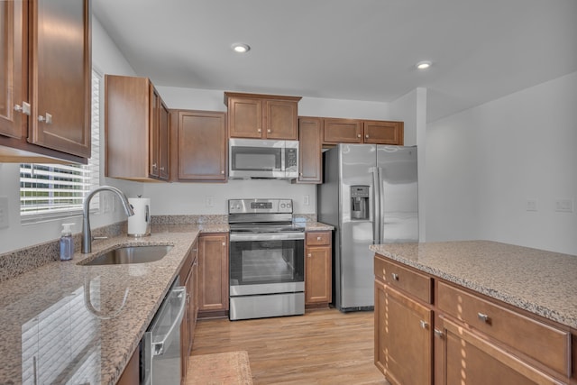 kitchen with light stone countertops, sink, light hardwood / wood-style floors, and appliances with stainless steel finishes