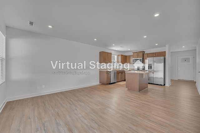 kitchen with a center island, light stone countertops, light hardwood / wood-style floors, and appliances with stainless steel finishes