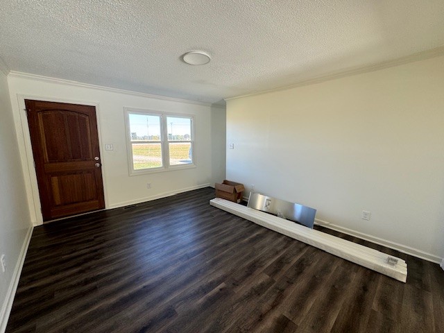 spare room featuring crown molding, dark hardwood / wood-style floors, and a textured ceiling