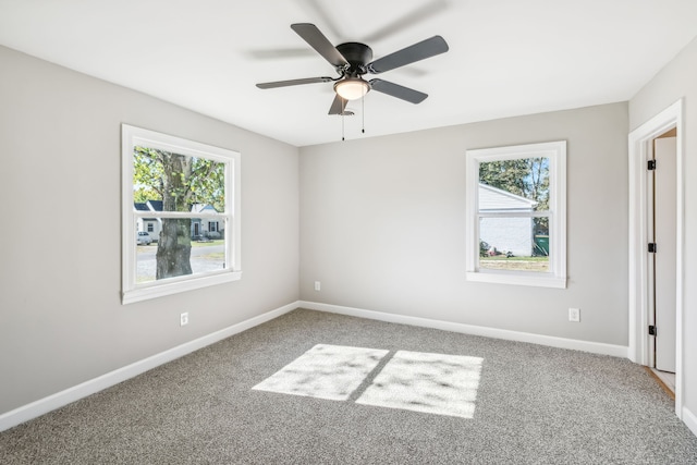 empty room with ceiling fan, a wealth of natural light, and carpet floors