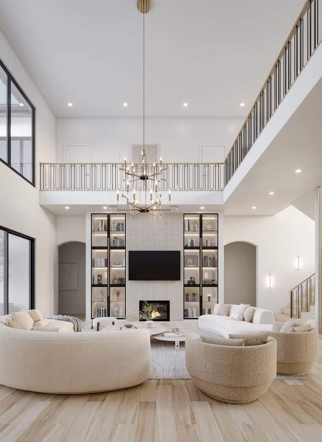 living room featuring a tiled fireplace, a towering ceiling, and light hardwood / wood-style floors