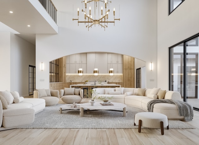 living room with an inviting chandelier, a high ceiling, and light wood-type flooring