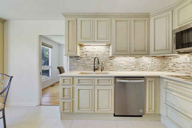 kitchen with tasteful backsplash, cream cabinets, stainless steel appliances, and sink