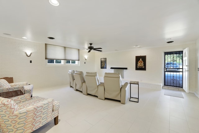 tiled cinema room with ceiling fan and brick wall