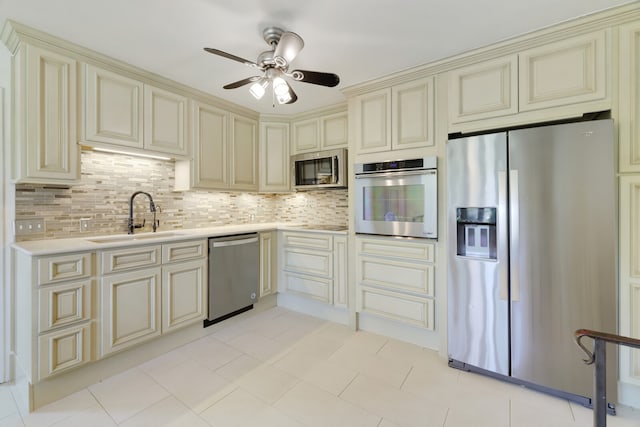 kitchen featuring appliances with stainless steel finishes, tasteful backsplash, sink, and cream cabinetry