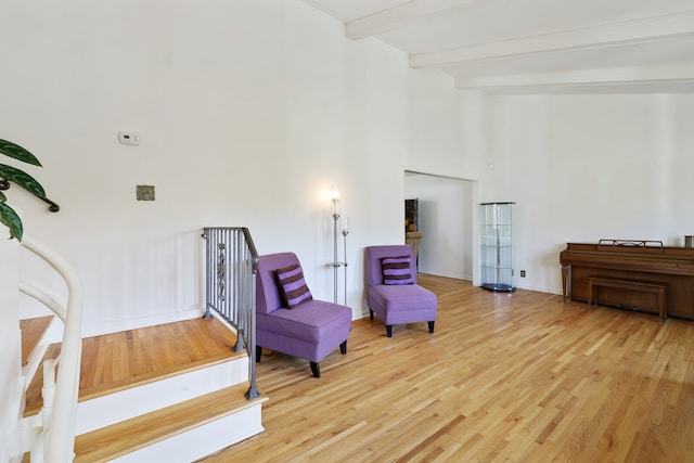 living area with beamed ceiling, high vaulted ceiling, and light hardwood / wood-style floors