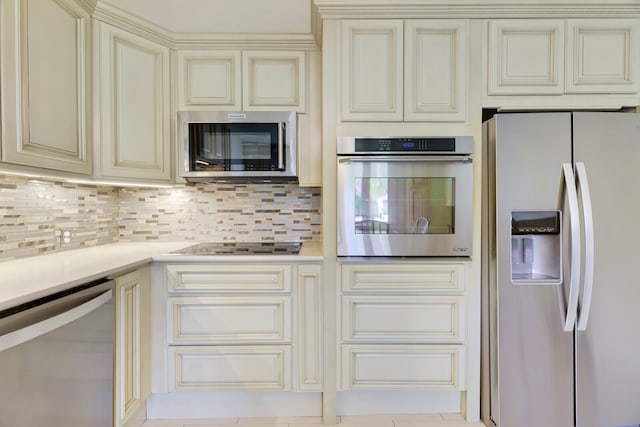 kitchen featuring decorative backsplash, appliances with stainless steel finishes, cream cabinets, and light tile patterned floors