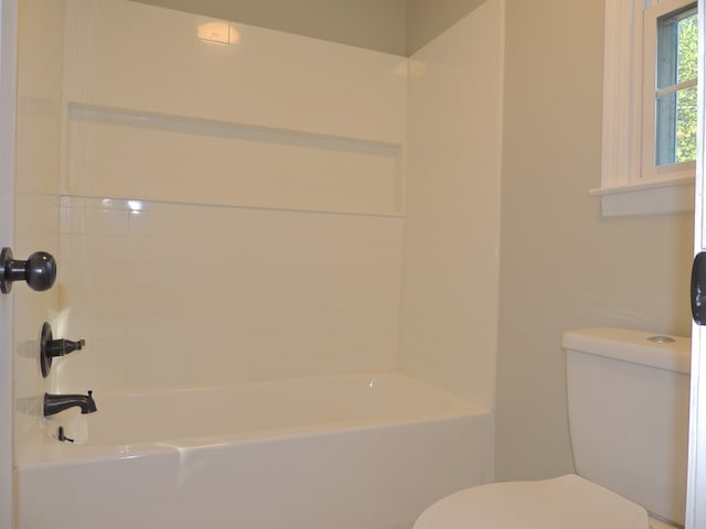 bathroom featuring tiled shower / bath combo and toilet