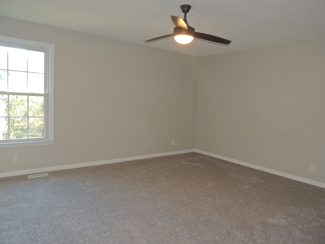 carpeted spare room featuring a textured ceiling and ceiling fan