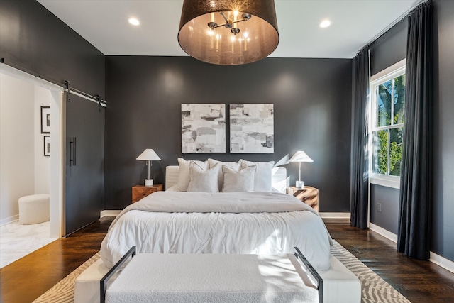 bedroom with a barn door and dark wood-type flooring