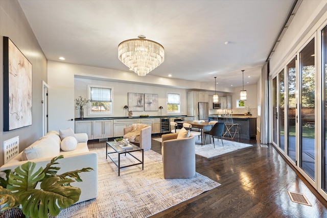 living room with an inviting chandelier, hardwood / wood-style floors, and beverage cooler