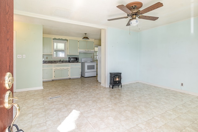 kitchen featuring sink, ceiling fan, a wood stove, and electric range