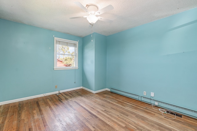 spare room featuring baseboard heating, hardwood / wood-style floors, a textured ceiling, and ceiling fan