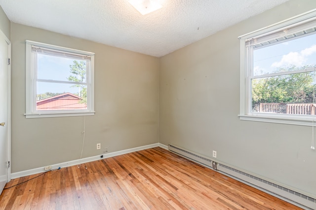 unfurnished room featuring a baseboard heating unit, a textured ceiling, light hardwood / wood-style floors, and plenty of natural light