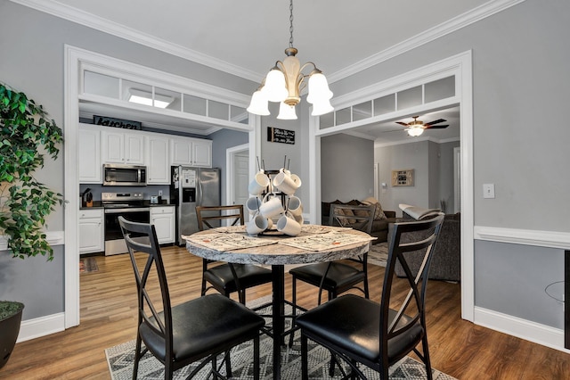 dining space featuring hardwood / wood-style flooring, ornamental molding, and ceiling fan with notable chandelier