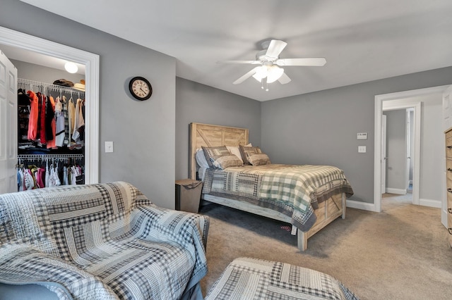 carpeted bedroom featuring a closet, a walk in closet, and ceiling fan