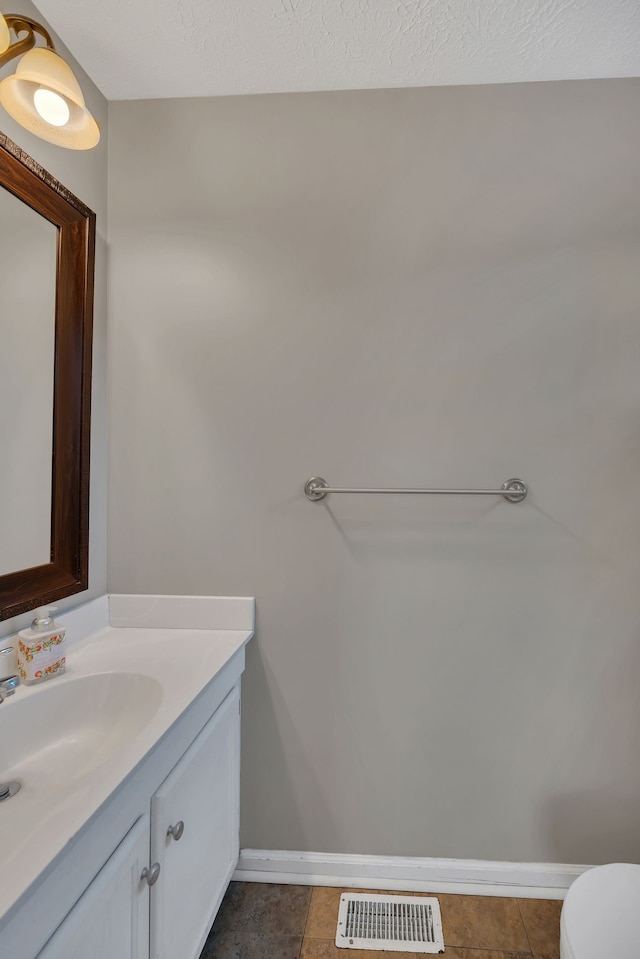 bathroom featuring toilet, vanity, a textured ceiling, and tile patterned floors