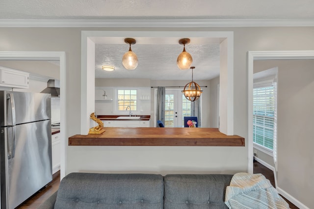 kitchen featuring butcher block counters, stainless steel refrigerator, sink, and decorative light fixtures